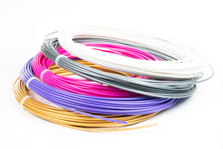 Top view of four colorful rolled filament 3D pen PLA isolated on white. Closeup of plastic bright...