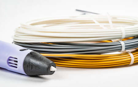 Closeup view of bunch of colorful rolled cables and childrens 3D printing pen isolated on white....
