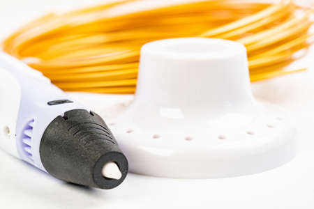 Closeup view of colorful rolled cables and childrens 3D printing pen isolated on white. Three bright...