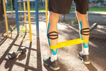 Unrecognizable male athlete training using resistance band outdoors.