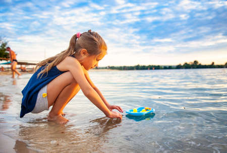 Caucasian girl playing with rubber duck toys on beach.の写真素材