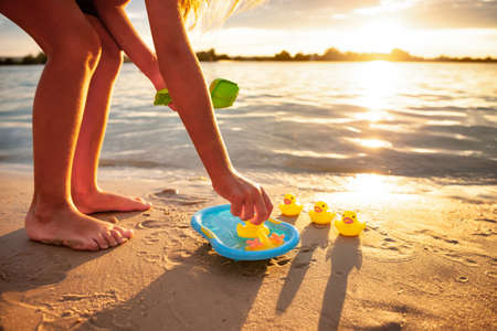 Unrecognizable kid playing with rubber duck toys on beach.の写真素材