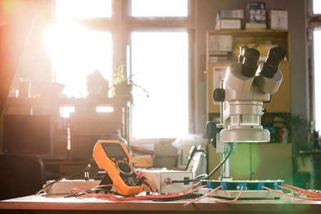 Large modern electron microscope. Microwave coaxial connector and electronic digital multimeter on workshop table. Research of high-frequency radio electronic components in a scientific laboratoryの写真素材