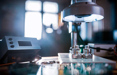 Large modern electron microscope. Microwave coaxial connector and electronic digital multimeter on workshop table. Research of high-frequency radio electronic components in a scientific laboratoryの写真素材