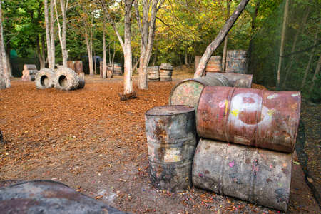 Old rusty barrels and damaged tires on a paintball baseの写真素材