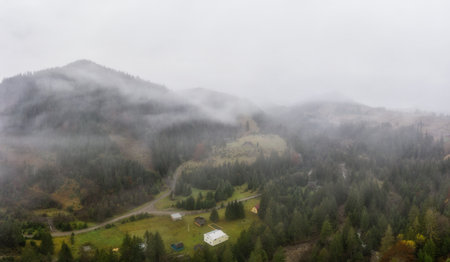 Rainy foggy and gray weather in the mountain valley of the Carpathians in Ukraine in small village Aerial panoramic drone shotの写真素材