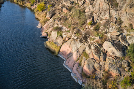 Among the large boulders, a smooth shining stream flows in the evening warm light in picturesque Ukraine.の写真素材