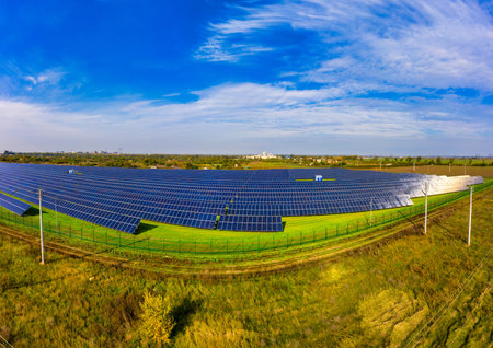 Huge solar power plant to use solar energy in a picturesque green field in Ukraine. Aerial panoramic...