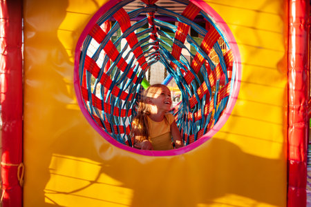 Little cute girl climbs through a bright long tunnel enjoying summer vacationの写真素材