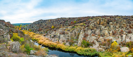 A large number of stone minerals covered with green vegetation lying above a small river in picturesque Ukraine and its beautiful natureの写真素材
