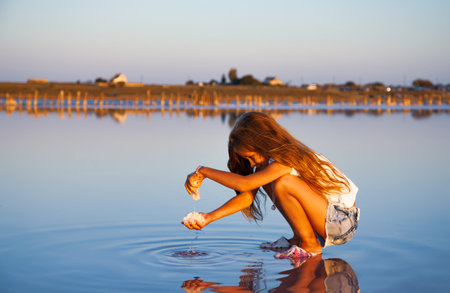 A little girl is looking at salt in a transparent water surface on a transparent backgroundの写真素材