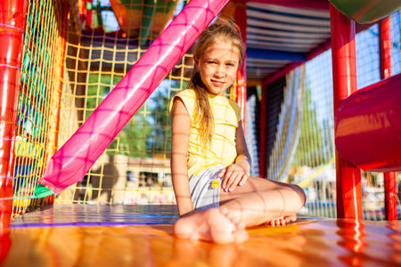 Funny girl sits on a colored mat in entertainment center with colorful equipmenの写真素材