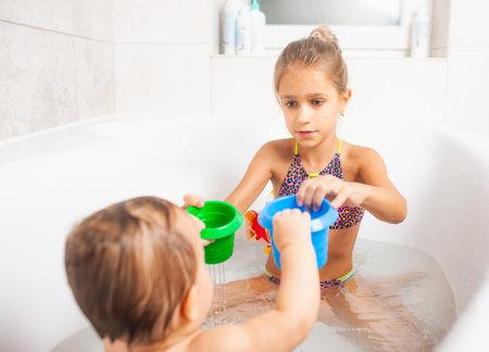 Girl playing with her little brother in the bathroomの写真素材