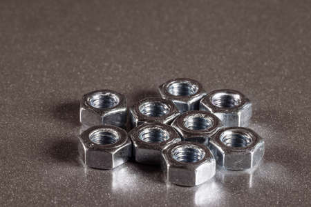 Several small shiny nuts on metal surface of an unidentified factory equipment. The concept of...