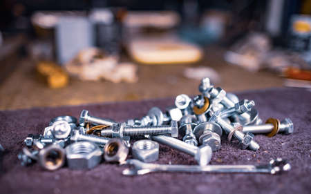 Metal nuts bolts and a wrench lie on the work table of the assemblerの写真素材