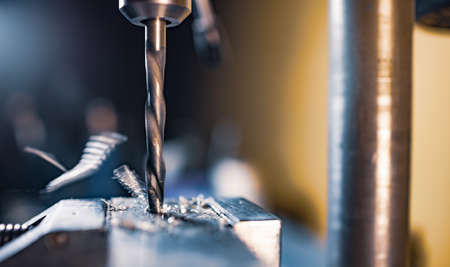 Drilling process with shavings close-up at the workplace in workshop