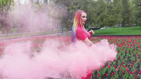 A girl with makeup with rainbow braids in red dress posing in red dressの写真素材