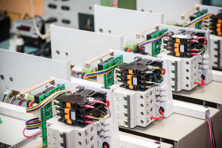 Metal mesh cases of power supply and wires are on a wooden table at the production of high-tech...