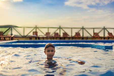A girl in a bright swimsuit with swimming goggles dives into a pool with clear transparent waterの写真素材