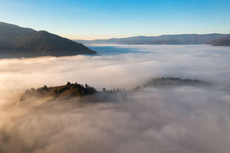 Mountains with terracotta and green trees growing under bright blue cloudless sky protrude from...