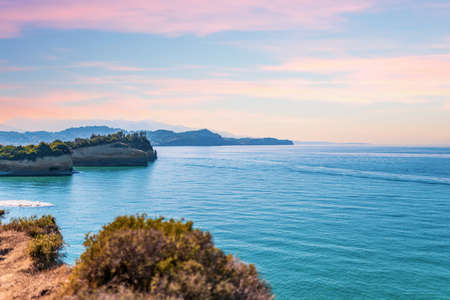 Boats sailing and leaving waves on Mediterranean sea of Greece close to Corfu island hill top against water horizon under cloudless skyの写真素材