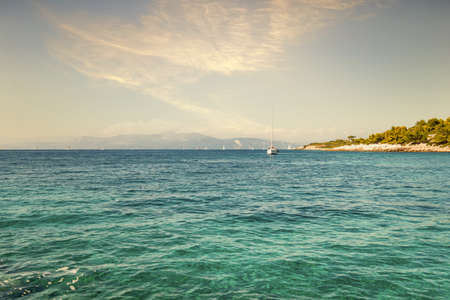 Anchored motorboat on calm water surface against Corfu island with buildings and mountains under...