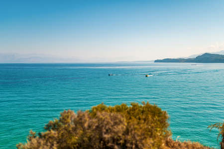 Boats sailing and leaving waves on Mediterranean sea of Greece close to Corfu island hill top...