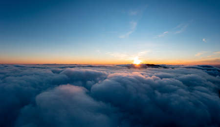 Sun shining brightly above white fluffy clouds at sunrise