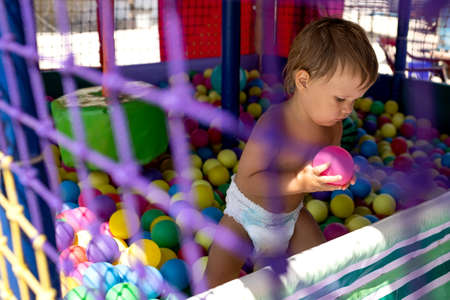 Boy in diaper with ball playing in playroom on weekend