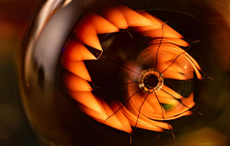 A bright fiery powerful glass incandescent lamp illuminates a dark room around with a fiery orange lightの写真素材