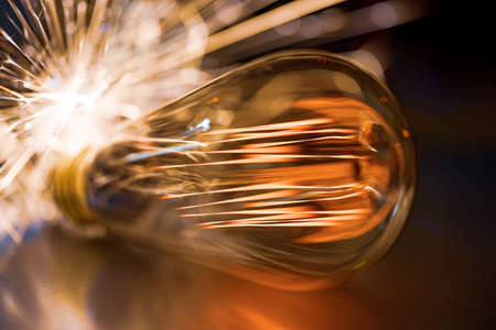 An old transparent glass incandescent lamp does not shine very brightly with an amber fiery light and quickly and sharply pourの写真素材