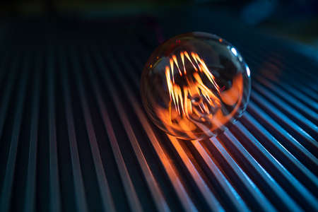 An incandescent lamp illuminates a dark room with orange lightの写真素材