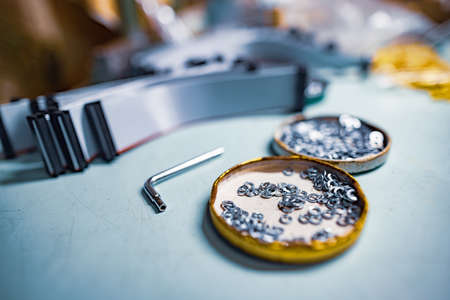 Many bolts and nuts, plastic components and tools lie on the table in the workshopの写真素材