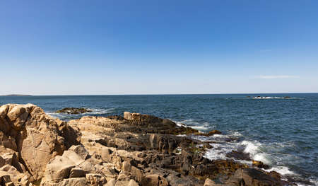 Tranquil Bulgarian seaside landscape with quiet blue reflective Black Sea and old dark rocky stones against bright sunny evening sunsetの写真素材