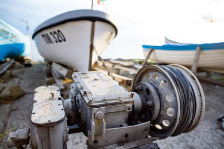 Winch with a rope on a pier with boats and boats against the skyの写真素材
