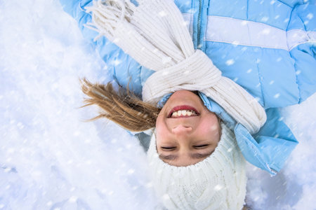 Pretty girl making angel on snow.の写真素材