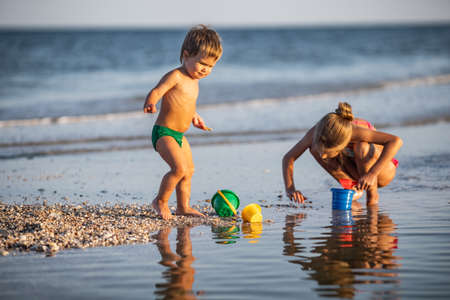 Older sister playing with younger brother aground near the shore on summer vacationの写真素材