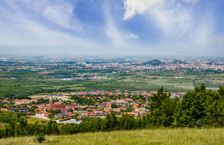 Ancient intermountain town Plovdiv with old residential houses and farm green fields, against backdrop of Rhodope Mountains and hills covered with evergreen spruce forests and cloudy overcast skyの写真素材