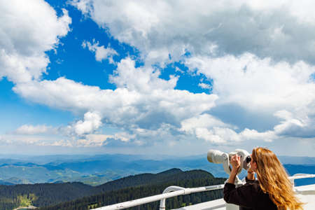 Curious girl tourist looks at mountainous wooded landscapes of mountain valley of Rhodope Mountains...