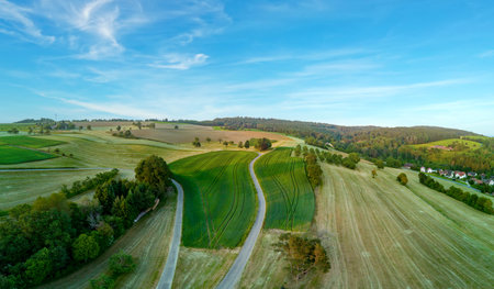 Panorama on valley with meadows, fields, forest and farms against a cloudy skyの写真素材