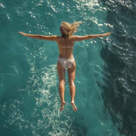 A woman gracefully leaps into clear turquoise waters, enjoying a sunny seaside adventure.の写真素材