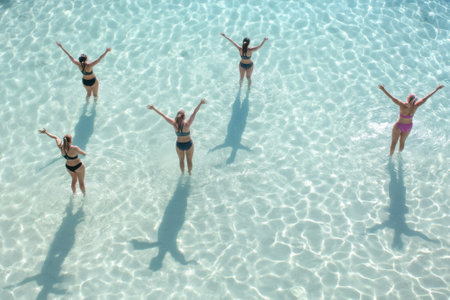 Friends celebrate and splash in the clear water under the bright sun at a tropical beach.の写真素材