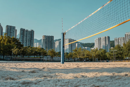 A sandy volleyball court in an urban park, with high-rise buildings and clear blue sky in the background.の写真素材