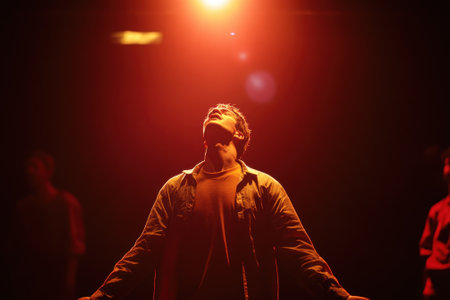 A performer stands with arms outstretched, illuminated by warm light, conveying deep emotion on stage.の写真素材