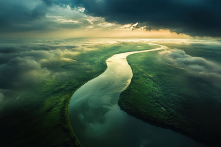 Aerial view of a meandering river surrounded by greenery, illuminated by the setting sun and dramatic clouds.の写真素材
