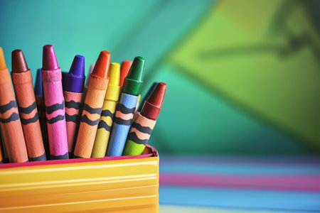 A collection of colorful crayons arranged in a yellow box, set against a vibrant and playful background.の写真素材