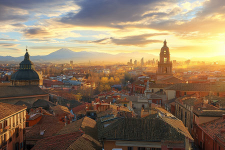 Sunlight bathes Madrid's rooftops with a stunning view of mountains as the day transitions to evening.の写真素材