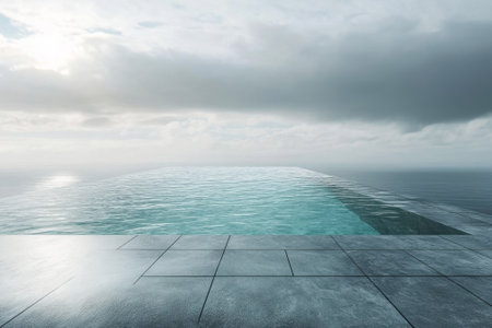 An infinity pool merges with the ocean at dawn, reflecting a cloudy sky and creating a tranquil atmosphere.の写真素材