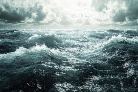 Turbulent ocean waves crash against each other under a cloudy sky, creating a dramatic seascape.の写真素材