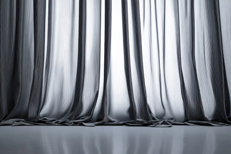 Soft gray curtains cascade elegantly to the floor, creating a tranquil atmosphere in a well-lit space.の写真素材